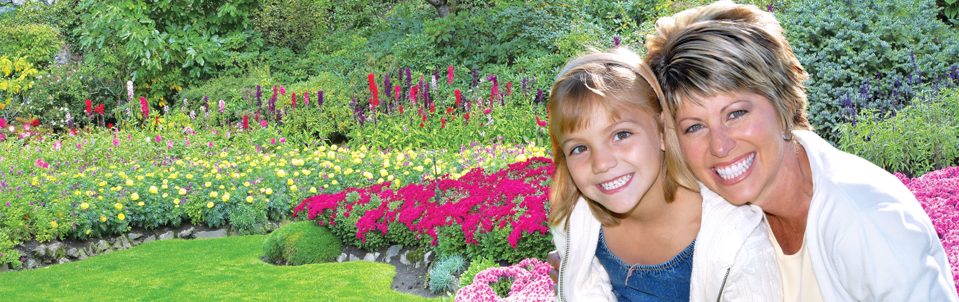 Mother and daughter smiling in a garden.